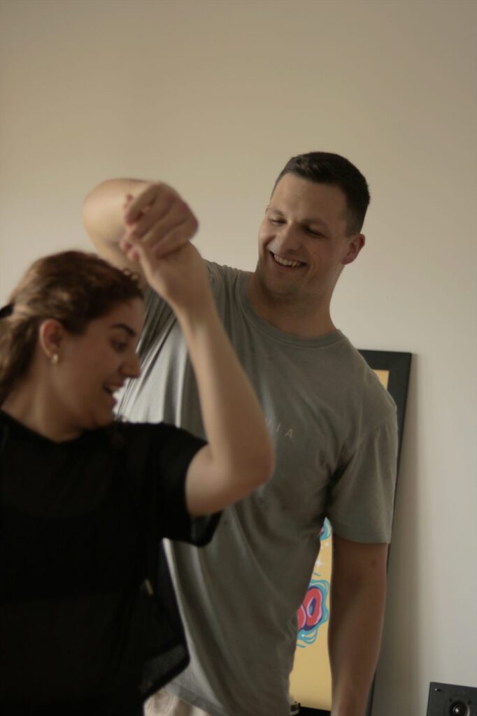 A couple laughing as one partner turns under the other's arm during a lesson