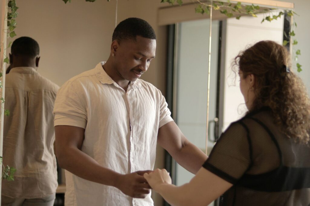 The teacher guides a student's hand position for partner connection
